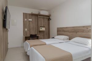 a hotel room with two beds and a desk at Hotel Praia Bonita Jatiúca in Maceió