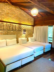 duas camas num quarto com uma parede de tijolos em Pousada Eco Luar em Igarassu
