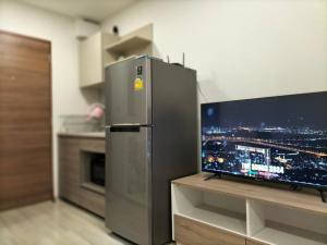 a stainless steel refrigerator in a kitchen with a flat screen tv at 1 Bed Room Near Saphanmai BTS, Don Mueang Airport in Ban Ko