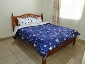 Una cama con una manta azul con estrellas. en Klimax Place, en Kiambu