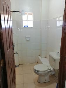 a white bathroom with a toilet and a sink at Klimax Place in Kiambu