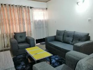 a living room with a couch and two chairs at Klimax Place in Kiambu