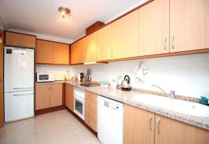 - une cuisine avec des placards en bois et un réfrigérateur blanc dans l'établissement Mirador de la Isla, à La Cala de Finestra