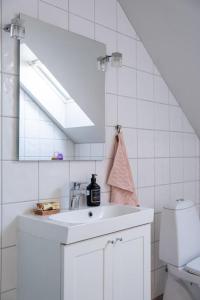 Baño blanco con lavabo y espejo en Lägenhet med vacker havsutsikt, en Visby