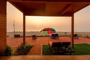 a table with a colorful umbrella in front of the beach at The O2H Agonda Beach Resort in Agonda