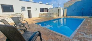 a swimming pool with chairs next to a house at Pousada Economic Pitangui in Pitangui