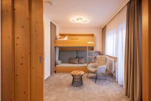 a small room with a bunk bed and a chair at Familien- & Vitalhotel Auenhof in Fulpmes