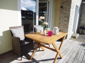 a wooden table on a patio with two chairs at Ferienwohnung Strand EG in Fehmarn