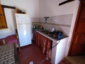 a kitchen with a white refrigerator and a sink at CABAÑAS LA LUCRECIA mono in Humahuaca