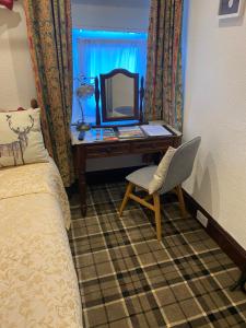 Cromarty View Guest House في دينغول: غرفة نوم مع مكتب مع مرآة وكرسي
