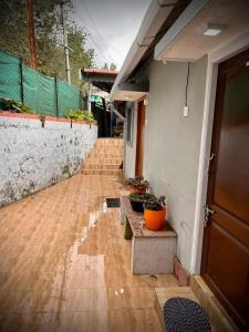 a porch of a house with pots of plants on it at Brickhouse in Kodaikānāl