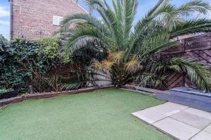 a yard with palm trees and a brick building at Luxurious & Spacious Townhouse in London