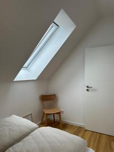 a bedroom with a skylight and a chair at Dümmerland Apartments in Lemförde