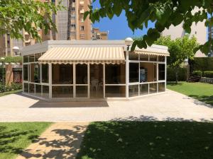Un edificio con tenda da sole in mezzo a un parco di Precioso apartamento en Urbanización junto al mar. ad Alicante