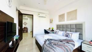 a bedroom with a bed and a flat screen tv at ZEN Suites - Golf Course Road Gurgaon in Gurgaon