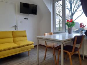 a living room with a table and a yellow couch at Pension Het Hoefijzer in Buren