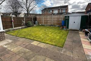 a backyard with a fence and a yard withgrass at Pass the Keys Stylish 3 bedroom home with free parking in Nottingham