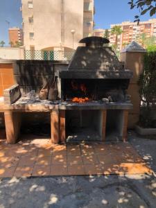 a stone fire pit in a park with a table at Precioso apartamento en Urbanización junto al mar. in Alicante