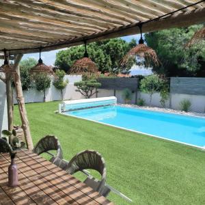 a backyard with a swimming pool and a wooden pergola at Belle villa contemporaine climatisee, piscine privee, 6 - 8 couchages, 3 chambres, wifi, à 3 km de la plage -LXDALI25B in Portiragnes