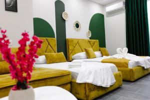 2 Betten in einem Hotelzimmer mit roten Blumen in der Unterkunft Andor Luxury Hotel in Durrës