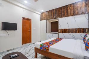 a bedroom with a bed and a tv on the wall at FabHotel Perams Grand Inn in Kondapur
