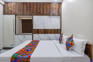 a bedroom with a white bed with a colorful blanket at FabHotel Perams Grand Inn in Kondapur