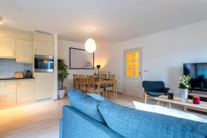 a living room with a blue couch and a kitchen at Jette Expo Duplex Residence in Brussels