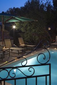 a swimming pool with chairs and an umbrella at night at Hostellerie du Cigalou - Teritoria in Bormes-les-Mimosas