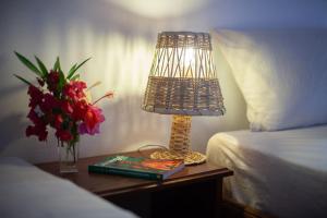 een lamp op een tafel naast een bed en een vaas met bloemen bij Fagapa Lodge in Guilor