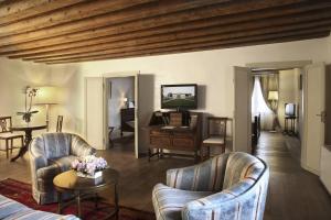 a living room with chairs and a table and a television at Hotel Villa Cornér Della Regina in Vedelago