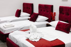 three beds in a room with red and white at Andor Luxury Hotel in Durrës