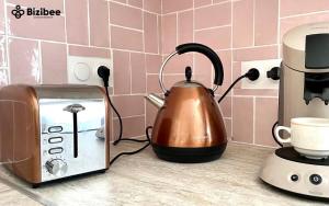 a tea kettle next to a toaster on a kitchen counter at Le Pink Lady Avenue de champagne in Épernay