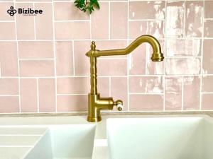 a gold faucet over a sink in a bathroom at Le Pink Lady Avenue de champagne in Épernay