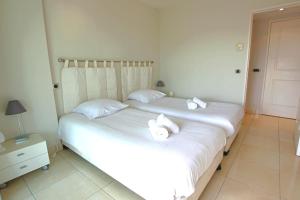 カンヌにあるFully equipped apartment with large terrace lounge areaの白いシーツとタオルが備わるベッドルームのベッド2台