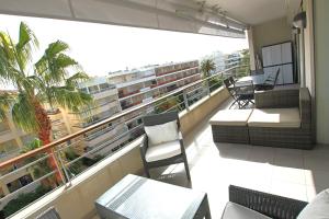 カンヌにあるFully equipped apartment with large terrace lounge areaのバルコニー(椅子、テーブル付)、大きな窓が備わります。