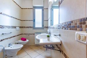 ein Badezimmer mit zwei Waschbecken, einem WC und einem Spiegel in der Unterkunft Appartamento Pinolo Trilo INT 9 - MyHo Casa in Alba Adriatica