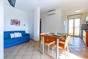 ein Wohnzimmer mit einem Tisch und einem blauen Sofa in der Unterkunft Appartamento Pinolo Trilo INT 9 - MyHo Casa in Alba Adriatica