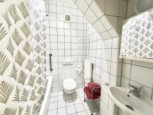 La salle de bains blanche est pourvue de toilettes et d'un lavabo. dans l'établissement Picobello Pension, à Görlitz