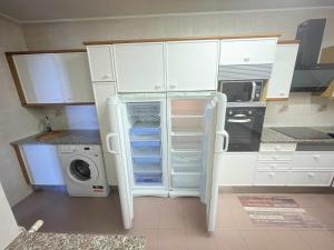 a kitchen with white cabinets and a washing machine at Villa Giulia between the sea and the mountains in Sant Vicenç de Montalt