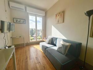 a living room with a blue couch and a large window at Aparthotel Riviera - Grimaldi AC - Promenade des Anglais - BALCON VICTOR HUGO 2 in Nice