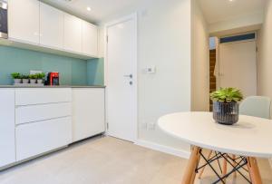 a kitchen with white cabinets and a table at Split Level Studio at West Hampstead by Concept Apartments in London