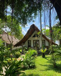 a small white house with a thatch roof at Villa Paradise in Bukit Lawang