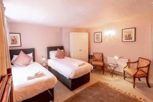 two beds in a room with two chairs and a table at The Old Vicarage Hotel & Restaurant in Bridgwater