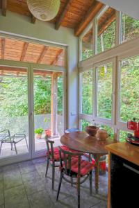 a dining room with a table and chairs and windows at La Maison entre Deux Rivières The River Mountain House - Nohèdes in Nohèdes