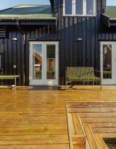 two benches on a wooden deck with a building at Charming Retreat in the Heart of Tórshavn in Tórshavn