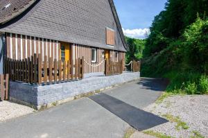 a house with a wooden fence next to a driveway at Ferienhof Verse Ferienwohnung Waldblick in Lennestadt