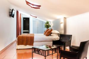 a bedroom with a bed and a chair and a table at Hôtel Cloitre Saint Louis Avignon in Avignon