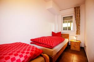 Ferienhof Verse Ferienwohnung Kornkammer في لينهشتات: غرفة نوم مع وسادتين حمراء ونافذة