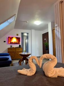 two towel swans sitting on the floor of a living room at Cetățuia - Ultra-Central Râșnov Stay - Parking and Nature Close to Bran, Dino Parc and More in Râşnov