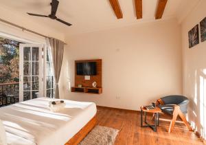 a bedroom with a bed and a tv and a chair at Moustache Bhimtal Luxuria, Nainital in Bhīm Tāl